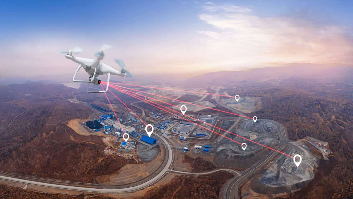 Drone inspecionando grande usina de enriquecimento de local industrial com marcadores de rastreamento gps ao nascer do sol.