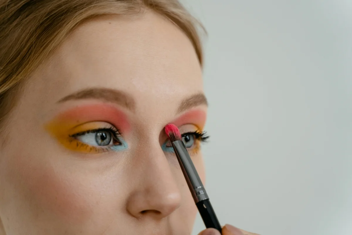 Mulher maquiando os olhos com sombras coloridas - maquiagem