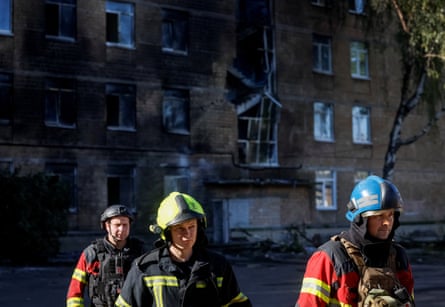 Three firefighters outside a smoking school building