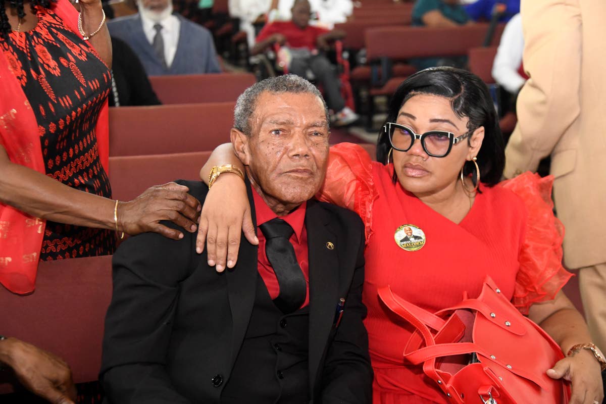 Mitsie Malcolm (right), Dervan’s sister, embraces a mourning Eric Malcolm, their father, at the funeral.